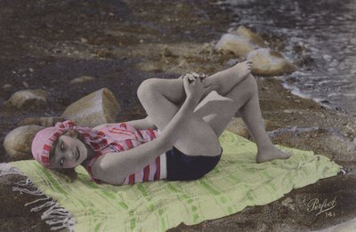 Jente som ligger på håndkle på stranden (farget bilde) av English Photographer
