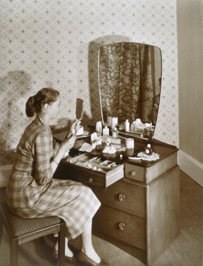 Kvinne ved sminkebordet hennes, c1955. av English Photographer