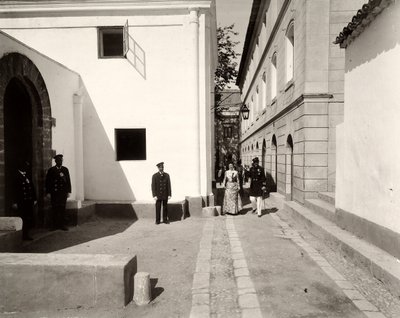 Menn i uniform følger en elegant kledd kvinne mot kirken til gården Lo Zucco, Sicilia, 1900 av Eugenio Interguglielmi