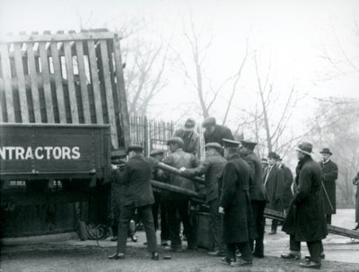 En mengde tilskuere står ved mens et neshorn blir losset fra en lastebil, av voktere, ved London Zoo i 1924 av Frederick William Bond