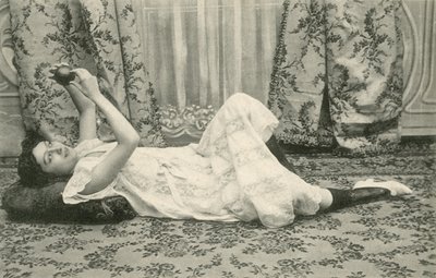 Jente som ligger på gulvet og holder en ball over hodet (s/hvitt-bilde) av French Photographer