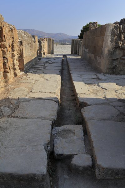 Det minoiske arkeologiske stedet Phaistos. Bred korridor med en dreneringskanal bak porten til nordfløyen som åpner seg fra den sentrale domstolen og fører til en indre gård ved siden av Royal Apartments. Phaistos, Kreta. av Minoan