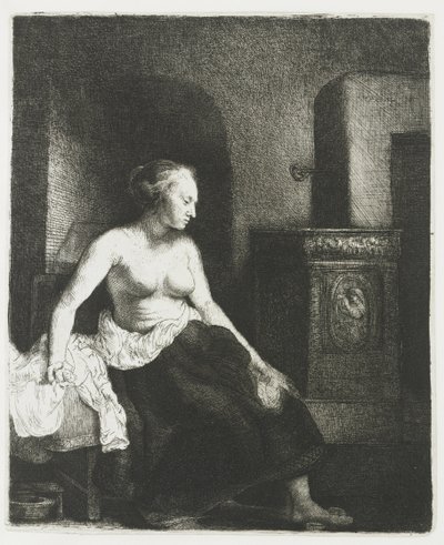 Kvinne som sitter halvkledd ved siden av en komfyr av Rembrandt van Rijn