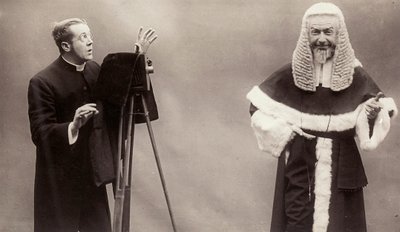 En mann i en sokk retter linsen på kameraet mot en mann kledd som en pave av Rotary Photographic Co Ltd