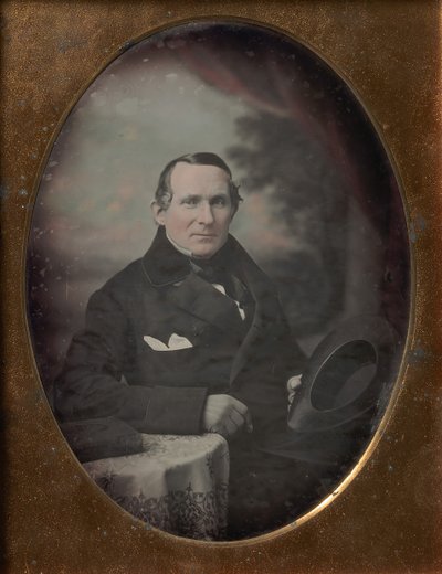 Mann med frakk og hansker, holder hatt, sittende foran malt utendørs bakteppe, 1840-tallet. av Samuel Broadbent Jr..