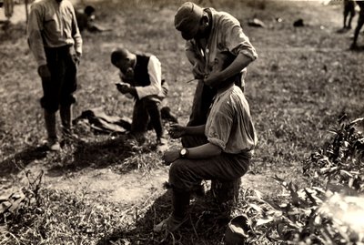 Østerrikske fanger under første verdenskrig i Bagnaria Arsa, Udine, Italia; i forgrunnen barberer en soldat en medsoldat, 02.04.1916 (s/hvitt-bilde) av Ugo Ojetti