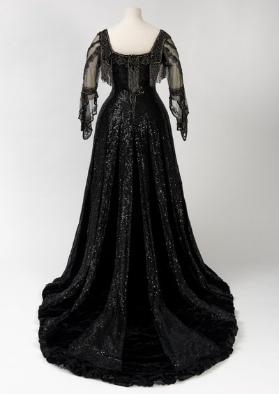 Sort kveldskjole i full lengde båret av dronning Alexandra, med dekorasjon av perler og paljetter og inkorporert dronning Alexandras signaturteip i svart silke og gull, laget av Barolet fra Knightsbridge, London 1908-1910 (silke og fløyel) av Unbekannt