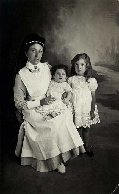 En "sykepleier" som poserer med barn på 1920-tallet. av William M. Timlin