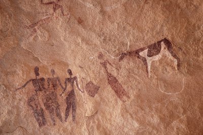 Bergkunst, forhistorie: Bergmaleri av en gruppe karakterer og en tofarget ku med store horn i et utsmykket ly, i Uweinat-massivet, Egypt. (Periode fra 8000 til 3000 år f.Kr.). Fotografering av Unbekannt
