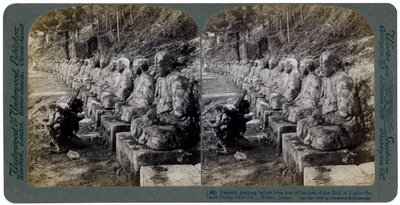Bonde ber foran en rad med statuer av lysets Gud, Daiya-elven, Nikko, Japan, 1904. av Underwood and Underwood