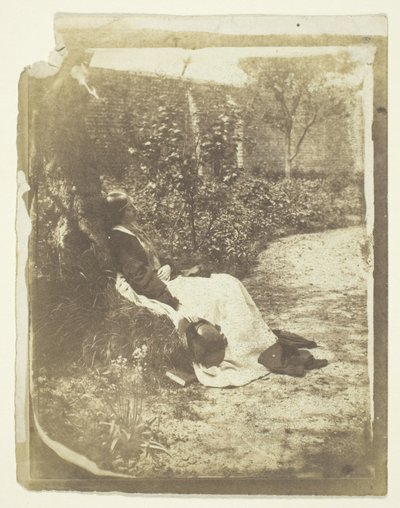 Mrs. Craik liggende i hagen med hatt og bok av Unknown