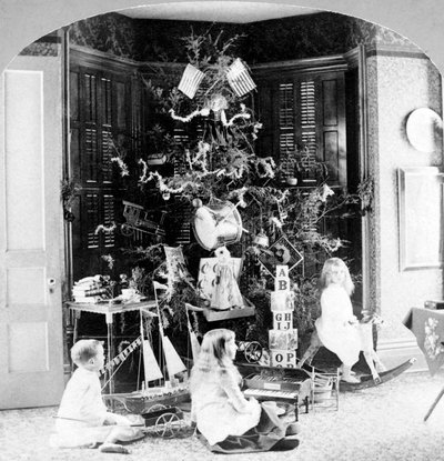 Barn samlet ved foten av treet omgitt av gaver på julemorgen. av Unknown photographer