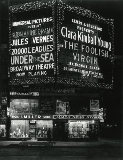 1554 Broadway på 46th Street, I. Miller Shoes; James Drug Store, og store markiser for filmer lyser opp ovenfor. av William Davis Hassler