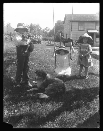 Barn med hund og valp samlet seg rundt en tauhuske på McCready Farm, Pennsylvania, ca. 1913 av William Davis Hassler
