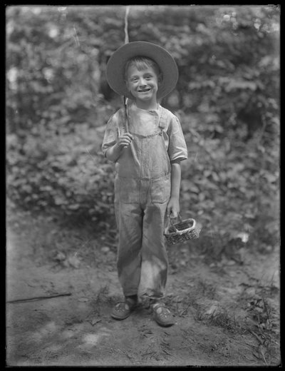 William Gray Hassler i stråhatt og kjeledress, med fiskestang og kurv i skogen, 20. august 1911 av William Davis Hassler