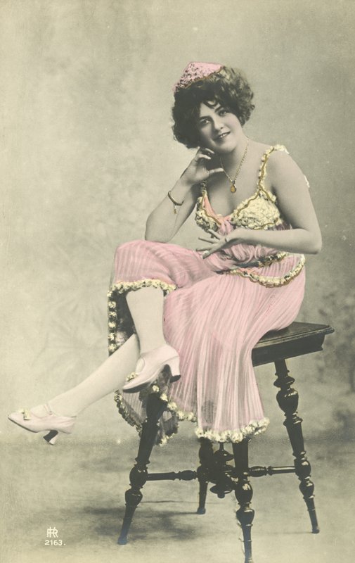 Skuespillerinne, med fint smil, i rosa kjole sittende på krakk av French Photographer