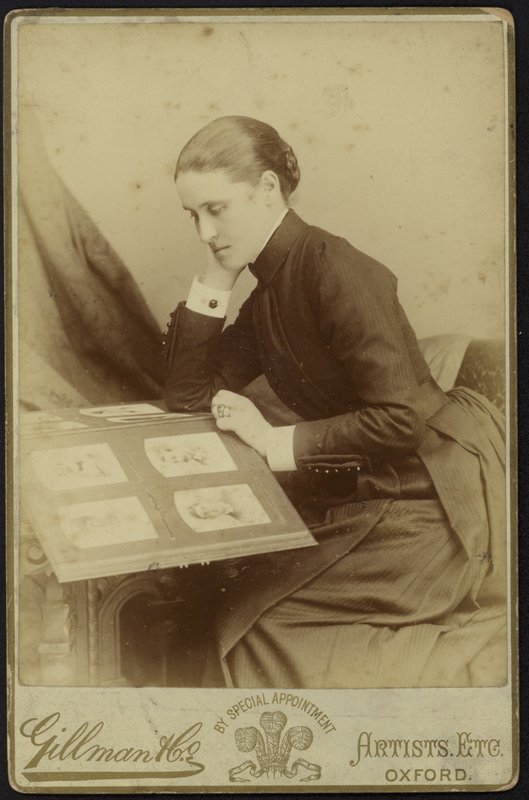 Figur av en kvinne som sitter og inspiserer et fotoalbum av English Photographer