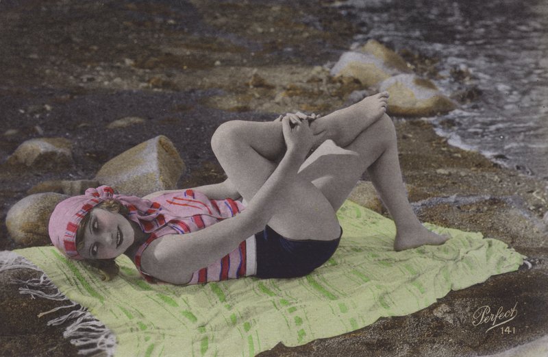 Jente som ligger på håndkle på stranden (farget bilde) av English Photographer
