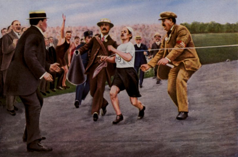 Lider av dehydrering og utmattelse. Den italienske friidrettsutøveren Dorando Pietri blir hjulpet over målstreken for å vinne maraton under de olympiske leker, London, 1908 av English Photographer