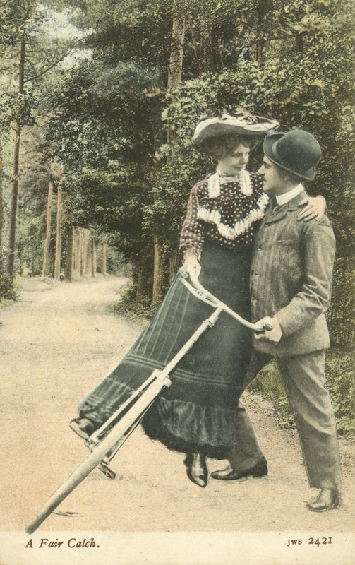 Kvinne faller av sykkelen i en manns armer (fargebilde) av English Photographer