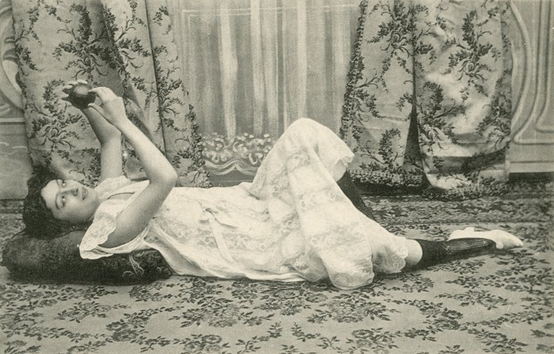 Jente som ligger på gulvet og holder en ball over hodet (s/hvitt-bilde) av French Photographer