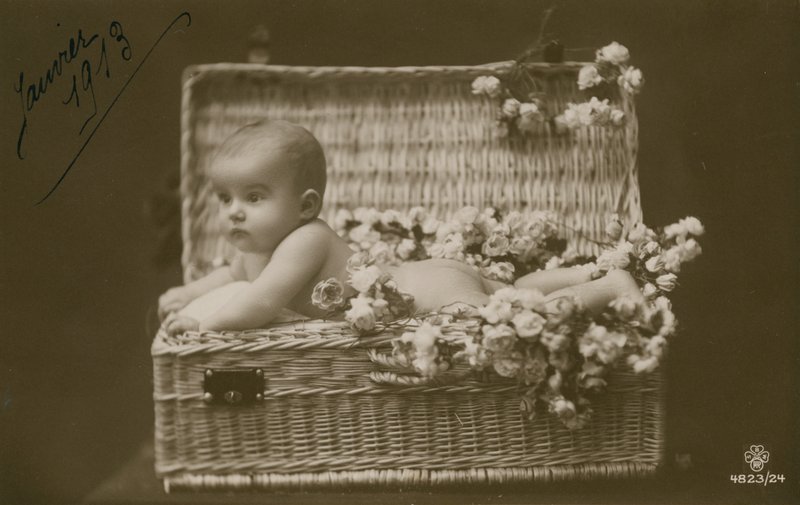 Postkort av en baby i en flettet kurv med blomster, sendt i januar 1913 av French Photographer