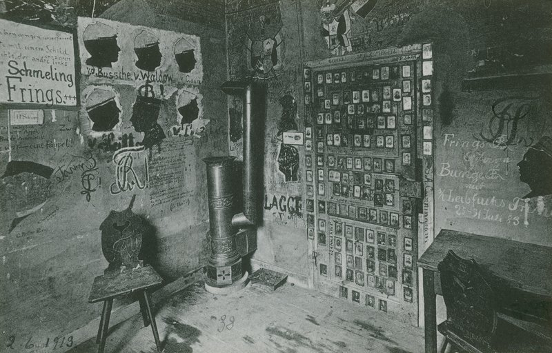 Et rom med vegger dekket av graffiti som refererer til viktige samtidige skikkelser som Bussche og Waldow. Postkort sendt i 1913. av German Photographer