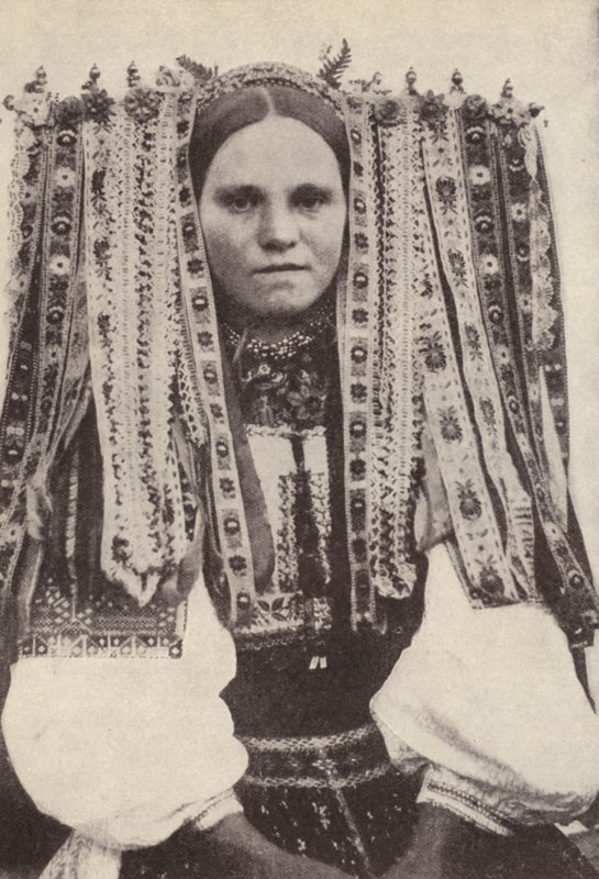 Tsjekkisk kvinne som har på seg en hodeplagg av bånd der hvert bånd angir en frier hun nektet i ekteskapet (s/hv-bilde) av Photographer Czech