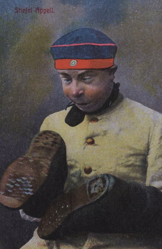 Tysk soldat ser på sålene på støvlene (farget bilde) av Photographer German
