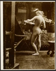 [Kvinnelig nakenmodell står i studio og holder en skissebok]