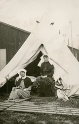 Sykepleier Eleanor Wibmer Jeffries og sykepleier Nellie Constance Morrice (til høyre) utenfor teltet sitt ved det 3. australske feltsykehuset med blomster plukket på bredden av Somme, ca. juni 1917