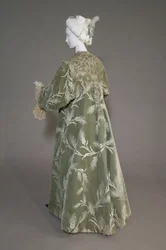 Bertha Palmers aftenfrakk, ca. 1902 (skrå utsikt bakover). Silkesateng med skåret fløyel i hvetemønster, metallisk trådblonde, silkemetallic dusker. Verdt, Paris.