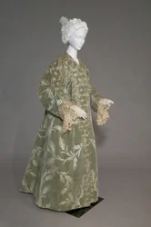 Bertha Palmers aftenfrakk, ca. 1902 (skrå utsikt foran). Silkesateng med skåret fløyel i hvetemønster, metallisk trådblonde, silkemetallic dusker. Verdt, Paris.