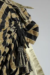 Aftenkjole, ca. 1884 (detaljvisning av mas). Silkesateng og kuttet fløyel, blonder, silketråddusker og frynser. Charles Frederick Worth, Frankrike.