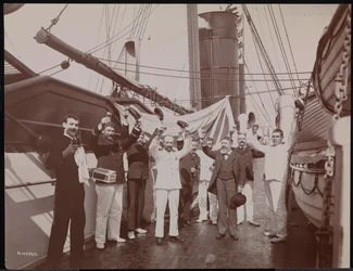Offiserer og mannskap skåler med champagne og sigarer på dekket av S.S. "Umbria", ca. 1897 (s/hv-bilde)