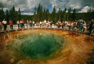 Parkbesøkende samles rundt det blågrønne, blomsterformede termiske bassenget. Yellowstone N…