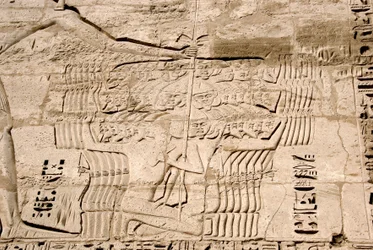 Egyptisk antikvitet: detalj av relieffene til den første pylonen som representerer fangsten av jagerfly som tilhører havets folk, fiender av Ramses III. Begravelsestempelet til Ramses III (1187–1156 f.Kr.). Luxor, Medinet Habou, Egypt