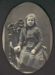 [Jente med ringer, sittende, trekvarts lengde], 1890-tallet.