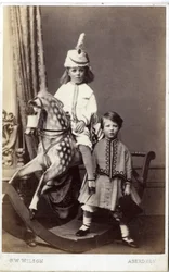 Ung jente med hatt på gyngehest med en annen jente stående, 1860-tallet (albumintrykk)