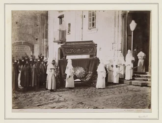 Begravelsesfølge av munker med spisse hetter ved inngangen til en kirke i Italia
