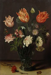Tulipaner med andre blomster i et glass på et bord
