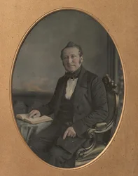 Sittende mann som peker på en passasje i en åpen bok, 1850-tallet.