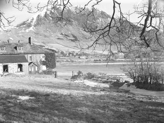 Anglers Hotel i Ennerdale med trær i forgrunnen og frossen innsjø og snødekte fjell utenfor