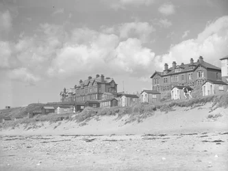 Utsikt fra Silloth-stranden med strandhytter og hus langs sjøen; sjølandskap; forfra
