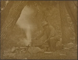 [Mann som lager mat over et leirbål i skogen]