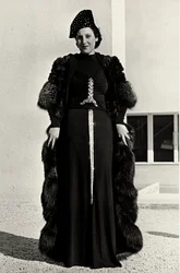 Modell i kveldskjole skapt av det italienske couturehuset "Dragoni". Skriften på artikkelen har en prangende paljettdekor i form av et sverd. En lue og pelsfrakk fullfører ensemblet. (s/hvitt bilde)