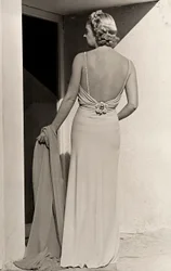 Modell sett bakfra har på seg aftenkjole fra couture-huset "Fumach". Artikkelen lar ryggen stå bar og er utsmykket med en juvelnål. (s/hvitt bilde)
