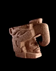 Førkolumbisk kunst, mayasivilisasjonen, førklassisk periode: steinskulptur som forestiller hodet til en mann som stiger opp fra munnen til en zoomorf gud som ligner himmelfuglen. 38 x 46 cm. Guatemala, Museo Nacional de Arqueología y Etnología