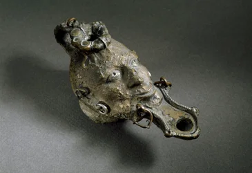 Romersk kunst: bronseoljelampe i form av et ansikt. 1. eller 2. århundre e.Kr. Spanias museum for Ampurias (Empurias)