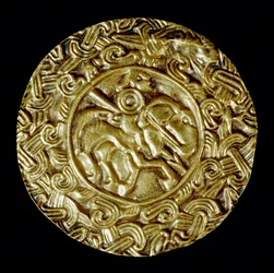 Arkeologi i middelalderen (middelalderen). Barbarkunst fra Lombardia: gullskive. I sentrum står en helgen til hest med spyd og rundt dyremotiver. Lombard kunst, rundt 600. Dim: 47 cm Italia, Cividale del Friuli, Arkeologisk museum